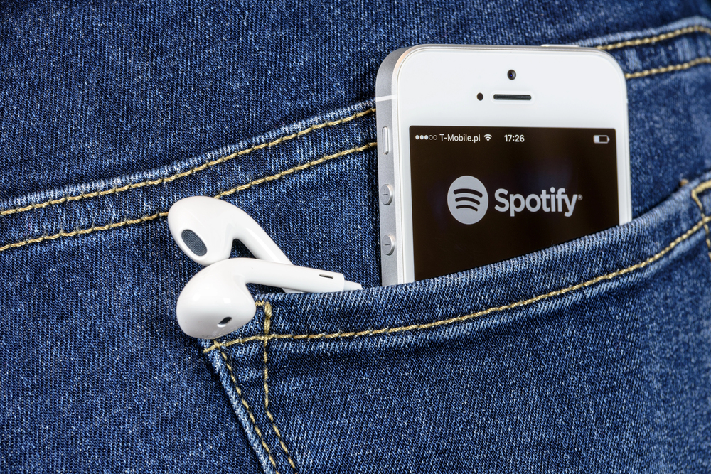 iPhone with Spotify App and headphones in back pocket of jeans