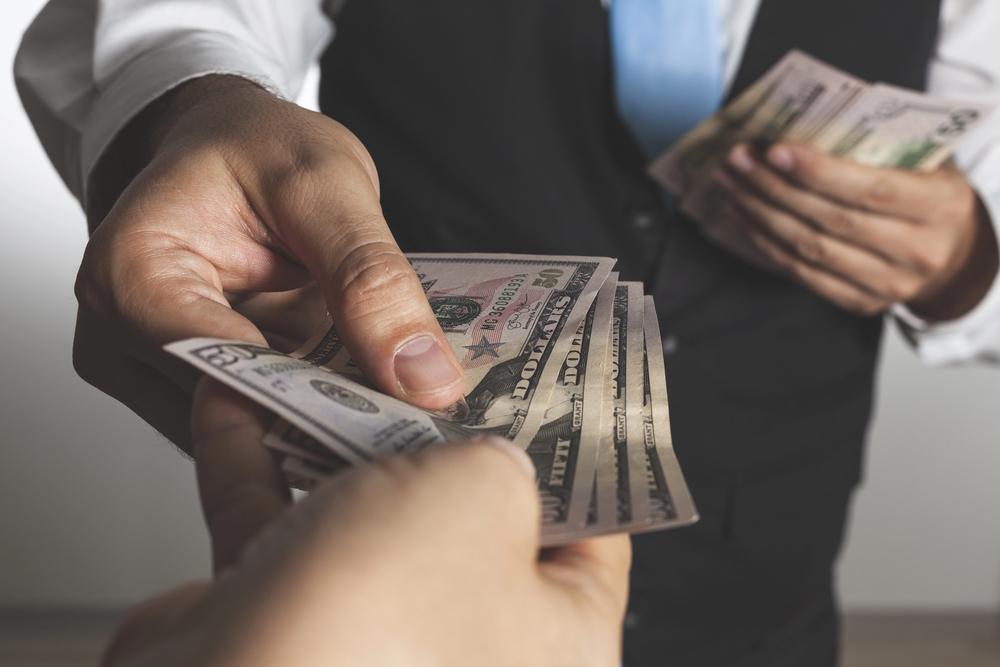 A closeup shot of a businessman giving money to another hand, doing exchanging — Photo