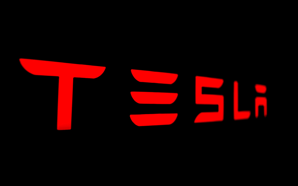 A red Tesla logo on a black background — Stock Editorial Photography