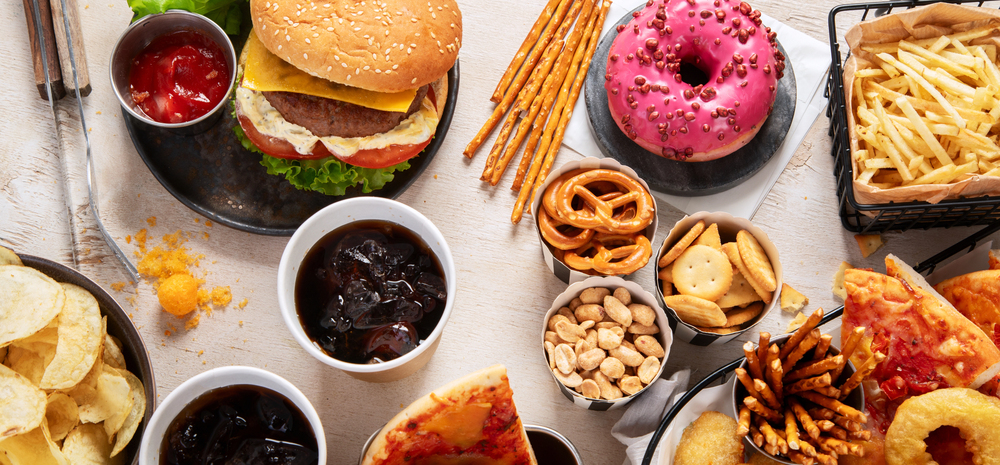 Various of american food, french fries, hamburgers, chips, popcorn, snacks and sauces on a white background, top view. panorama.