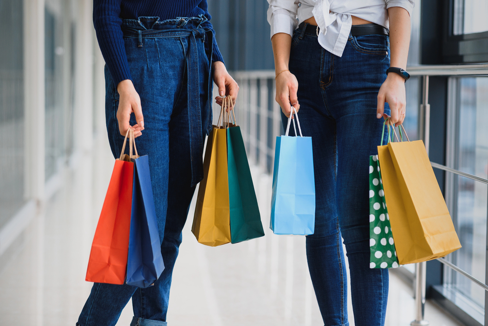 Two girl-friends on shopping walk on shopping centre with bags - stock image