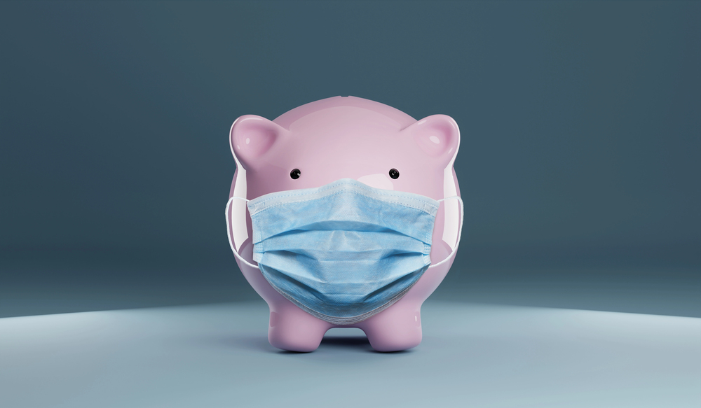 Piggy bank wearing a protective hygiene mask on blue background. 
