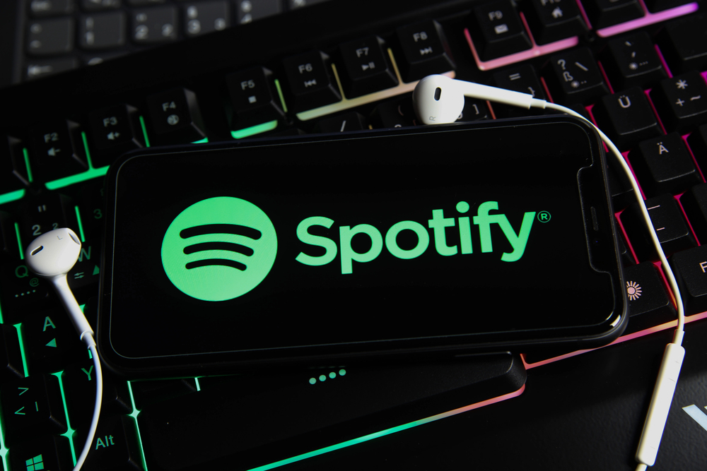 closeup of smartphone screen with logo lettering online music streaming service spotify on computer keyboard