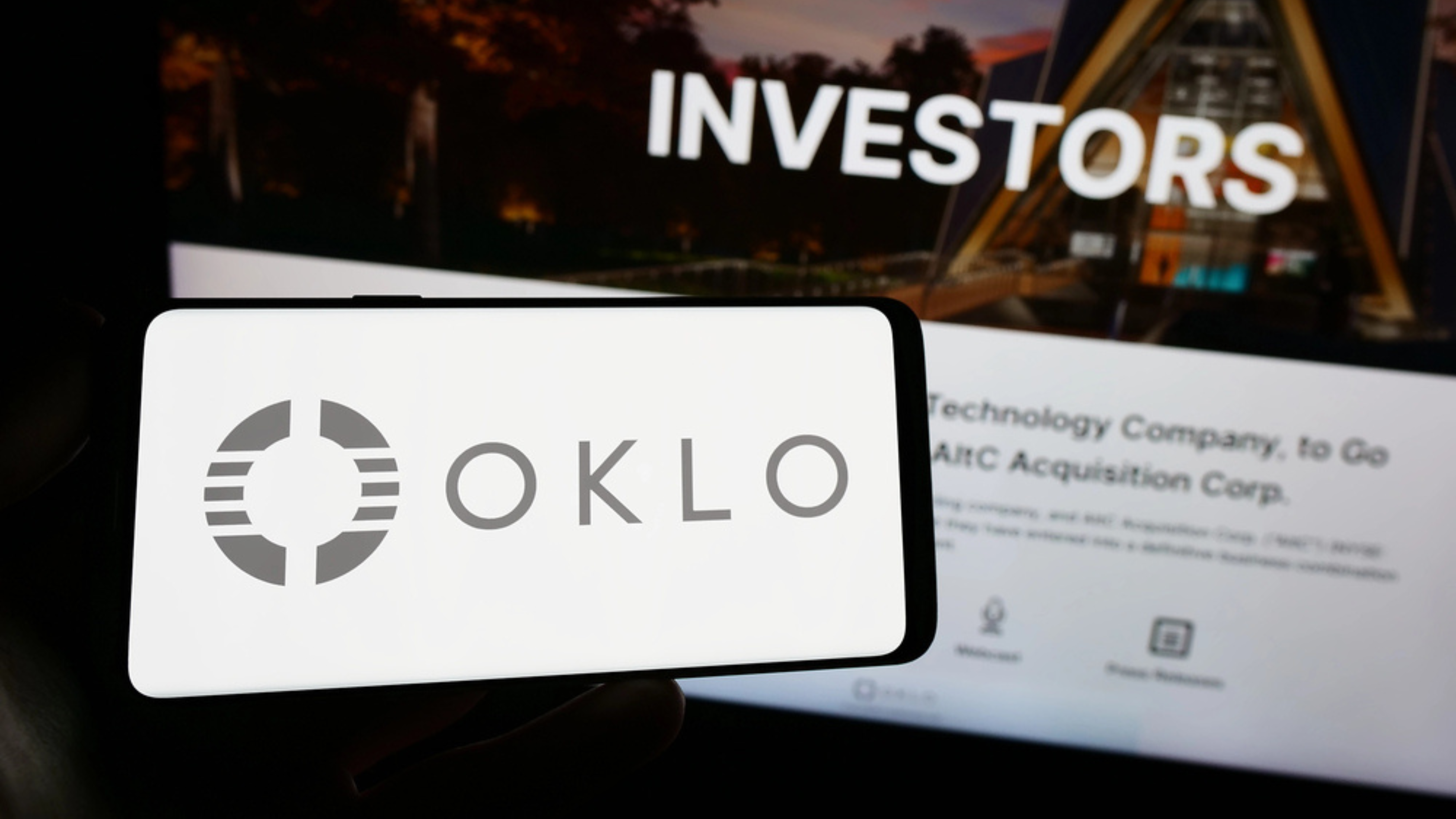 Person holding mobile phone with logo of American fission reactor company Oklo Inc. on screen in front of web page. Focus on phone display. - Stock Editorial Photography