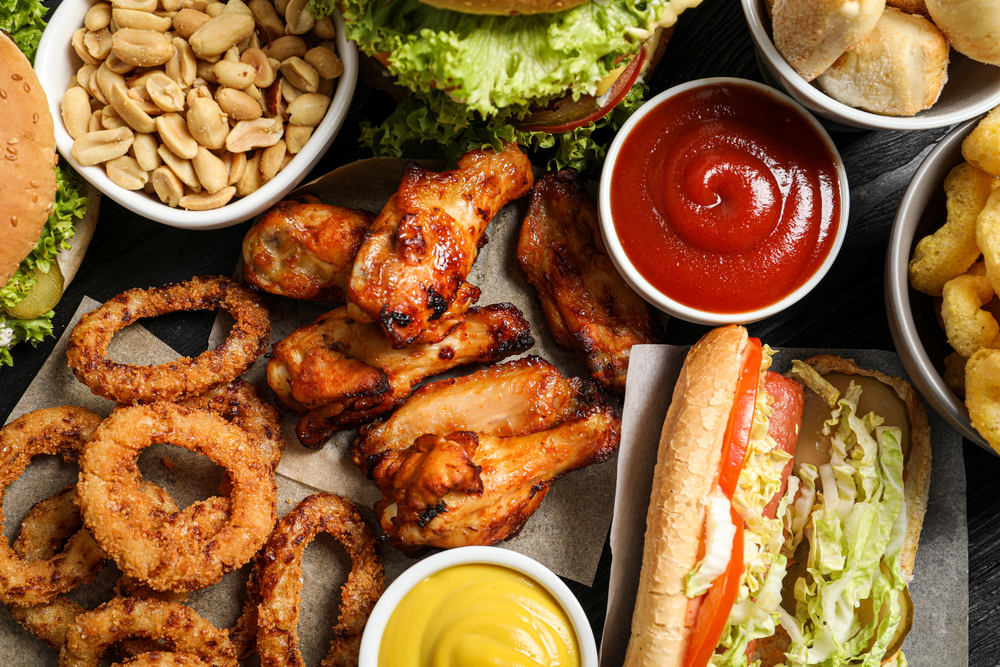 Chicken wings, onion rings and other fast food as background, top view - stock image