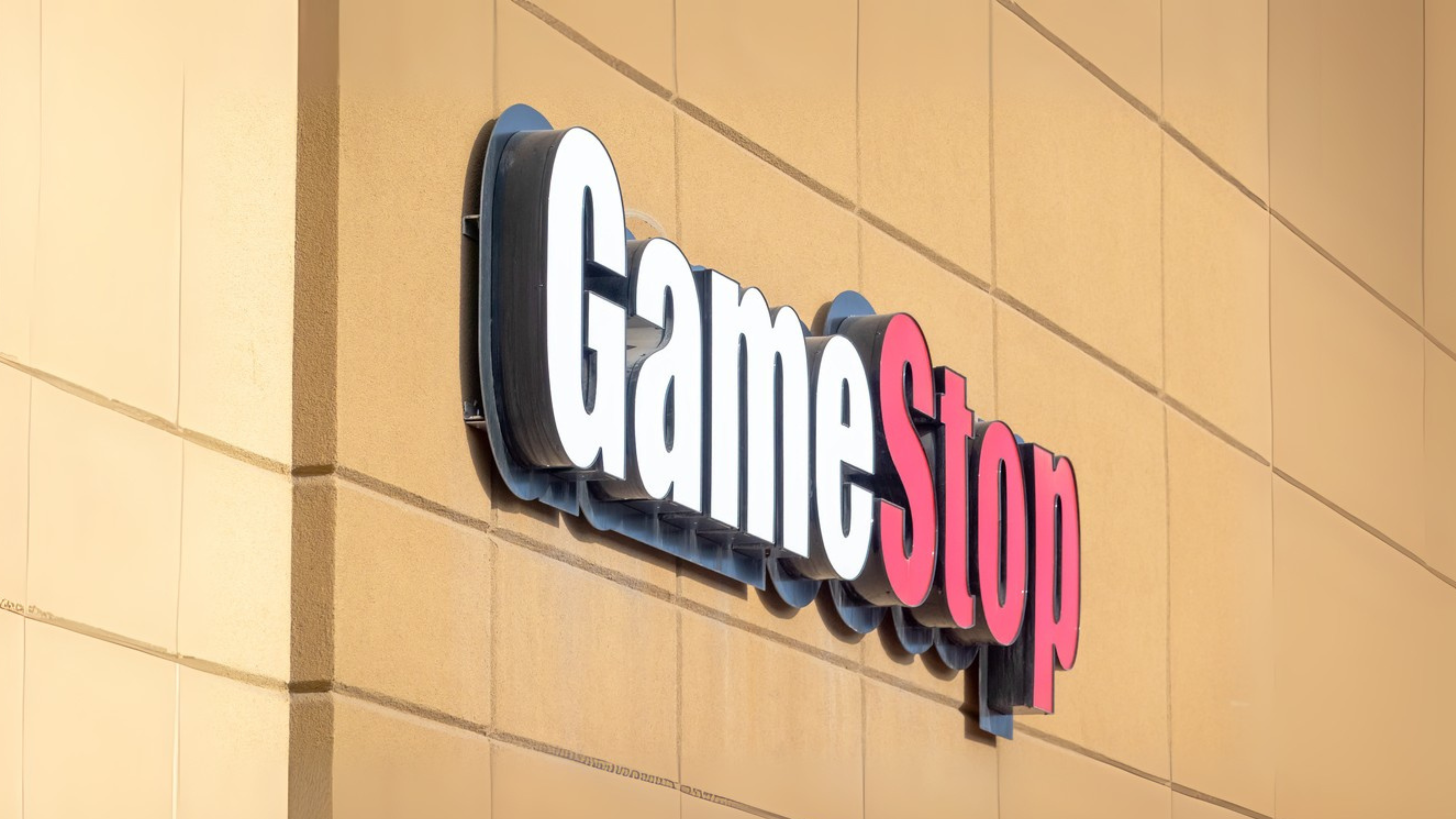 Calgary, Alberta, Canada. Apr 13, 2025. A close-up of a GameStop store sign featuring white and red lettering on a tan building.