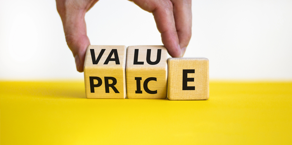 Value and price symbol. businessman turns wooden cubes and changes the word price to value or vice versa. beautiful yellow table, white background,