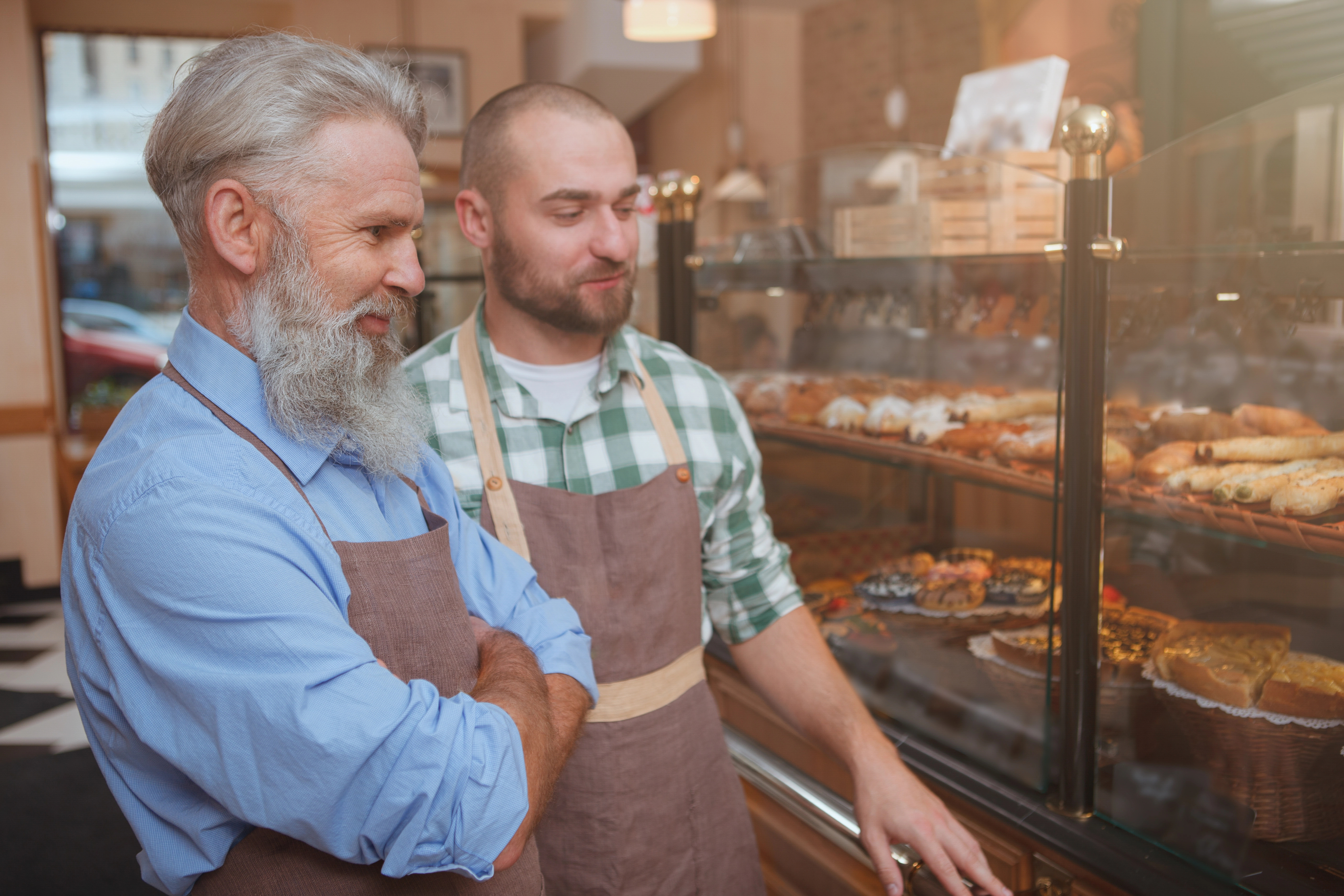 Older man and adult son working at a bakery together.
