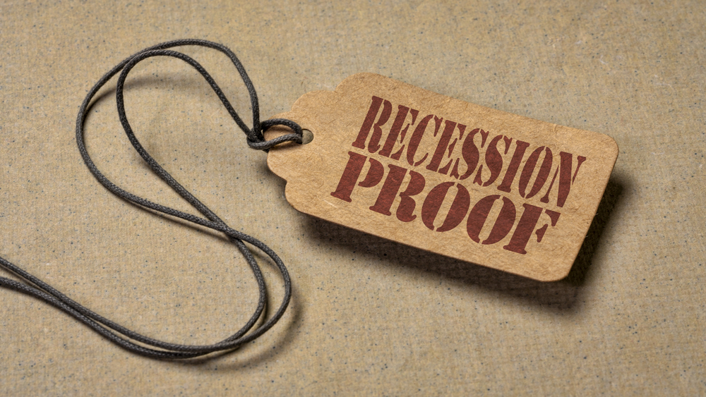Recession proof - red stencil text on a paper price tag against textured paper, marketing slogan