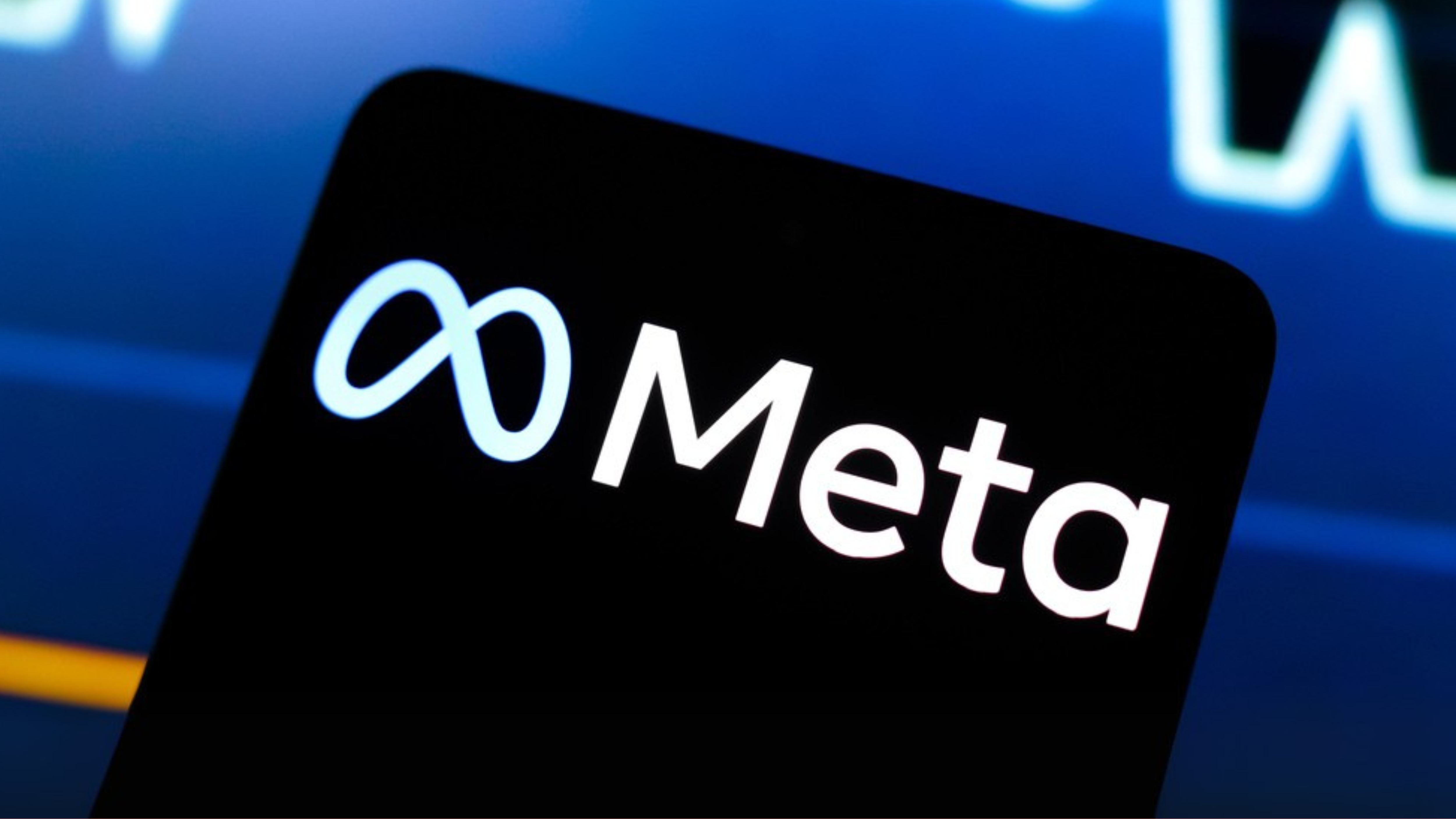 Meta logo is displayed on a smartphone screen and in the background, a stock market graph