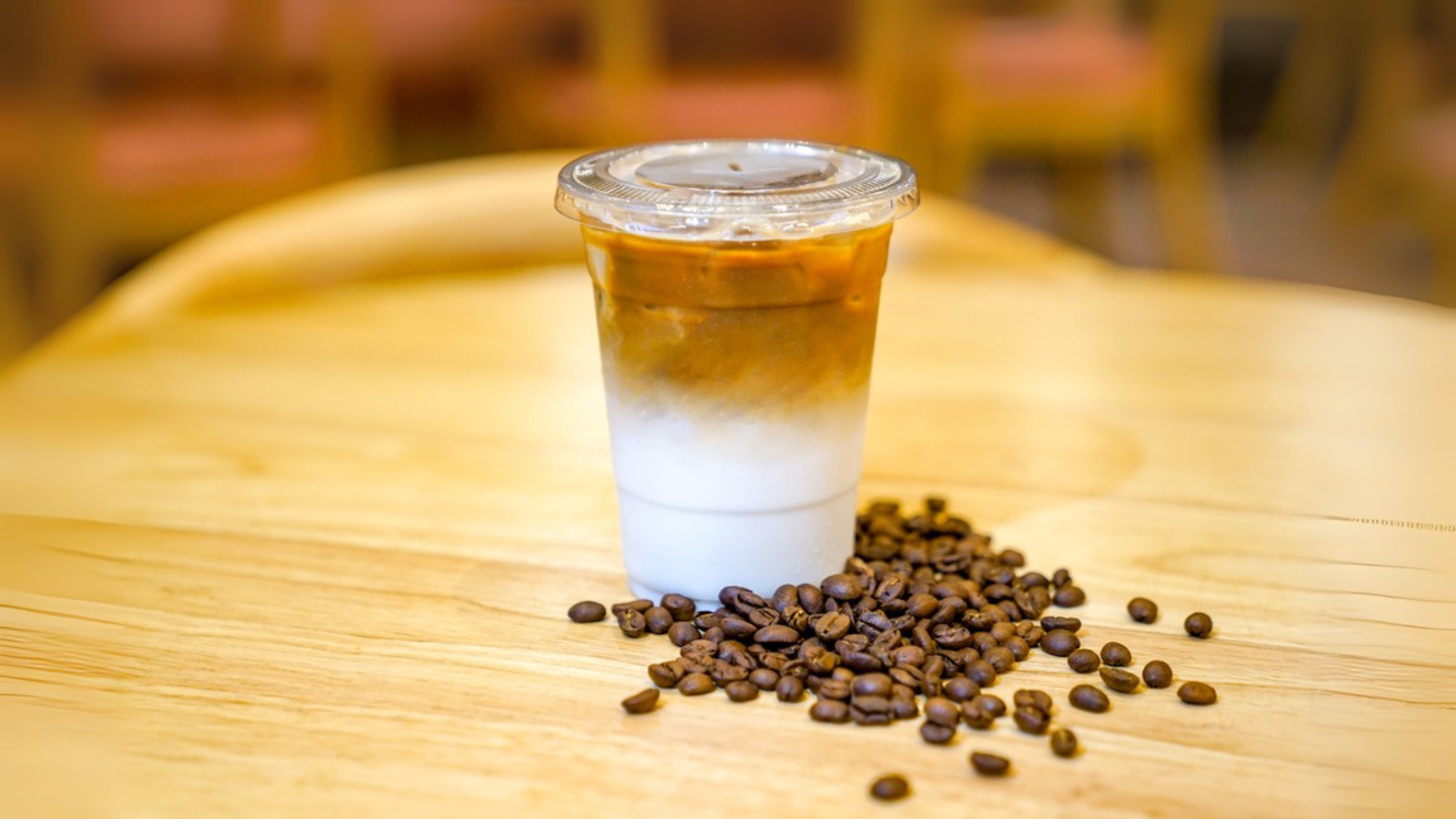 Take away Latte with Coffee bean around on the wood table — Photo