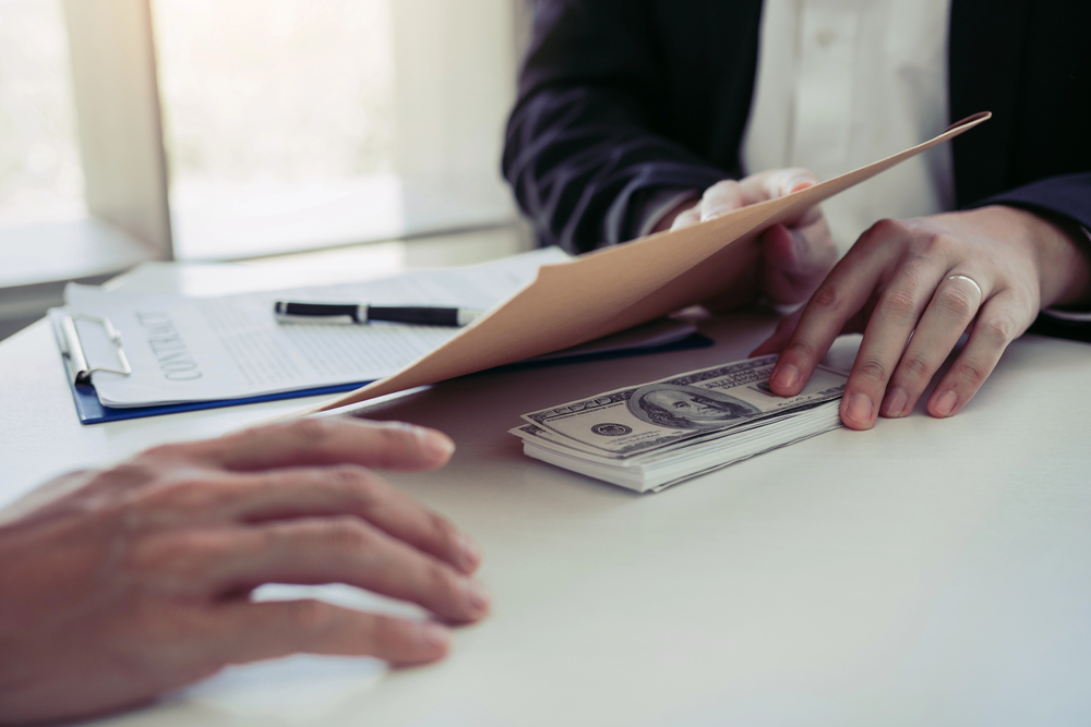 Businessman secretly giving a bribe by giving money bills