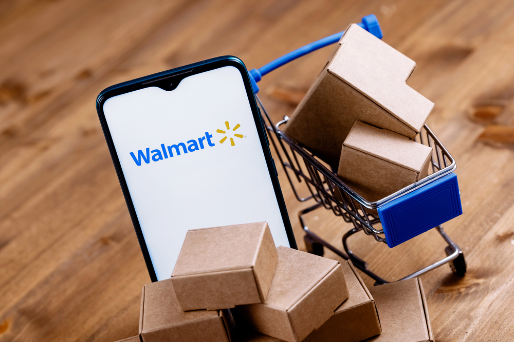 Kazan, Russia - Oct 20, 2021: Walmart is an American multinational retail corporation. Smartphone with Walmart logo on the screen, shopping cart and parcels.
