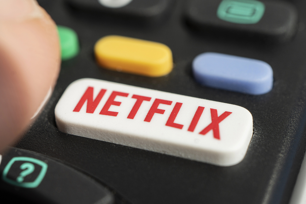 using a television remote with a dedicated netflix logo on the button. tv remote control with netflix logo.