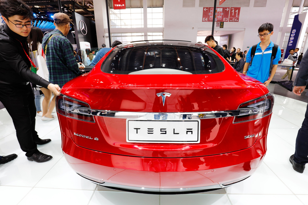 Visitors try out or look at a Tesla Model S electric car on display during the 14th Beijing International Automotive Exhibition, also known as Auto China 2016, in Beijing, China, 3 May 2016.