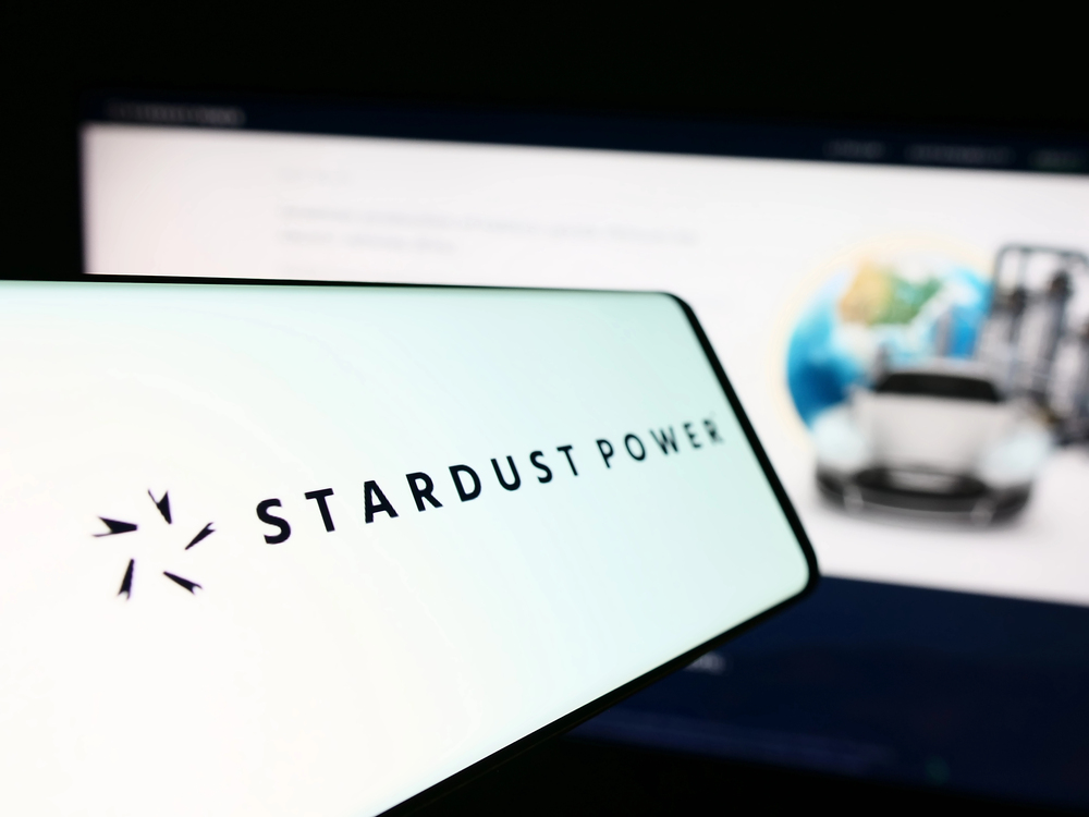 mobile phone with logo of american lithium refining company stardust power inc. in front of website. focus on center-left of phone display.