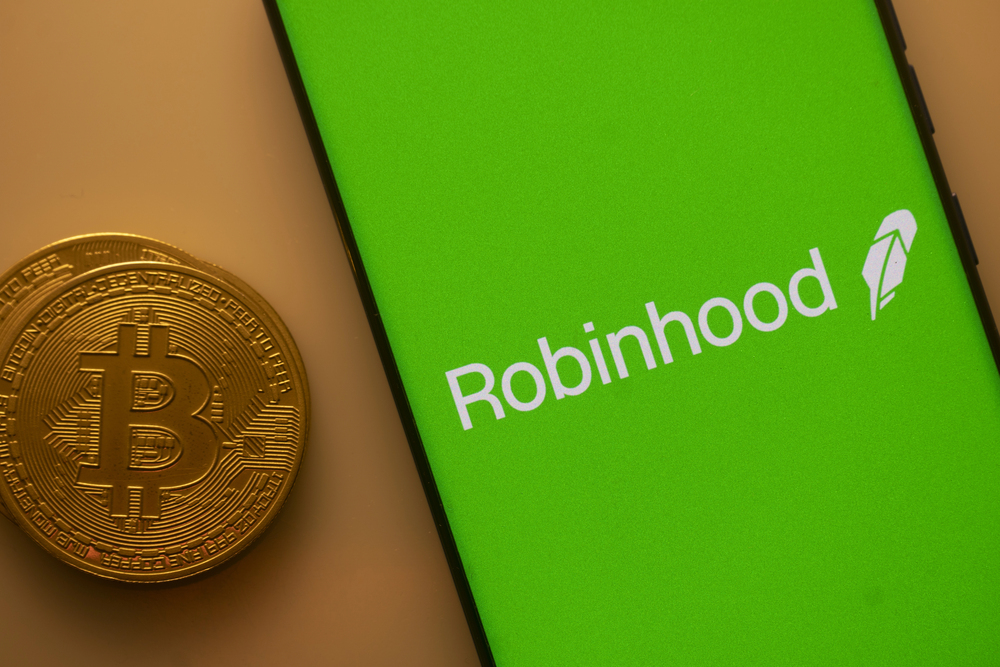 Robinhood logo on phone screen next to gold coins. 