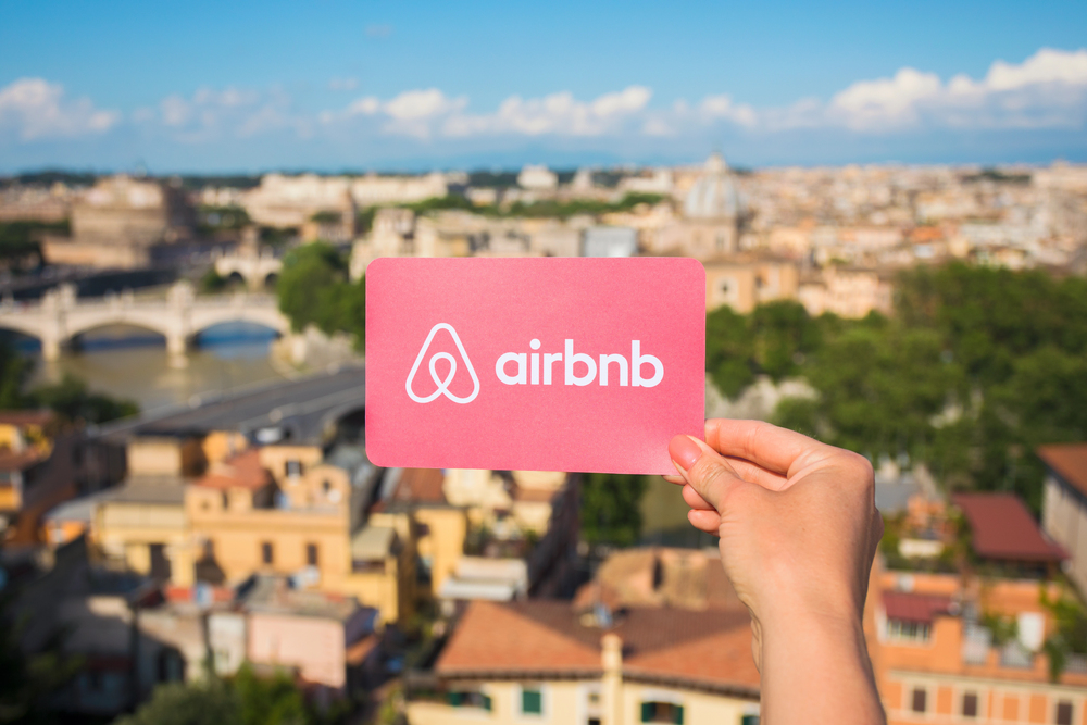 Airbnb logo on a business card, held up against a scenic overlook.