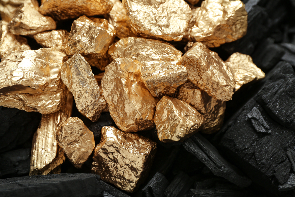 Golden nuggets on black charcoal.