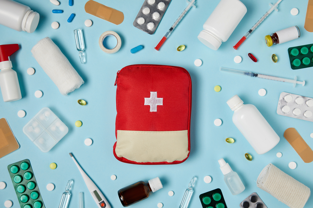 Assortment of medical objects, includig pills, syringes, and a first-aid kit.