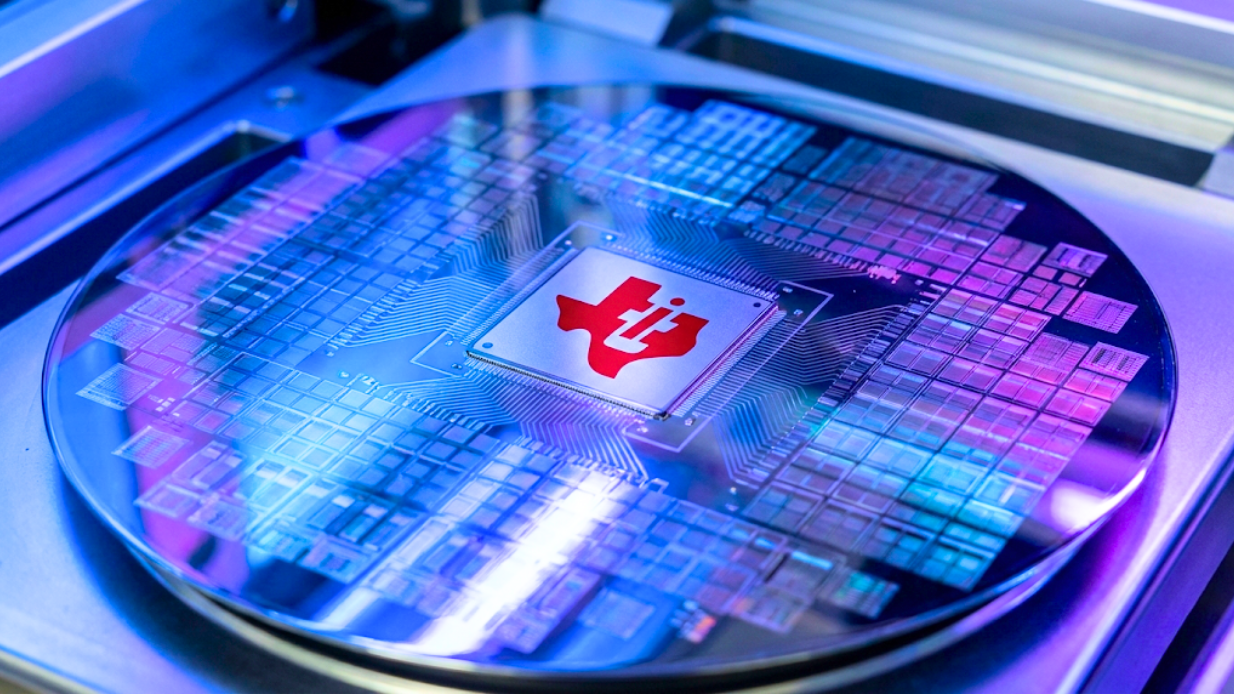 Texas Instruments logo on a silicon wafer, highlighting semiconductor manufacturing capacity and chip demand trends.
