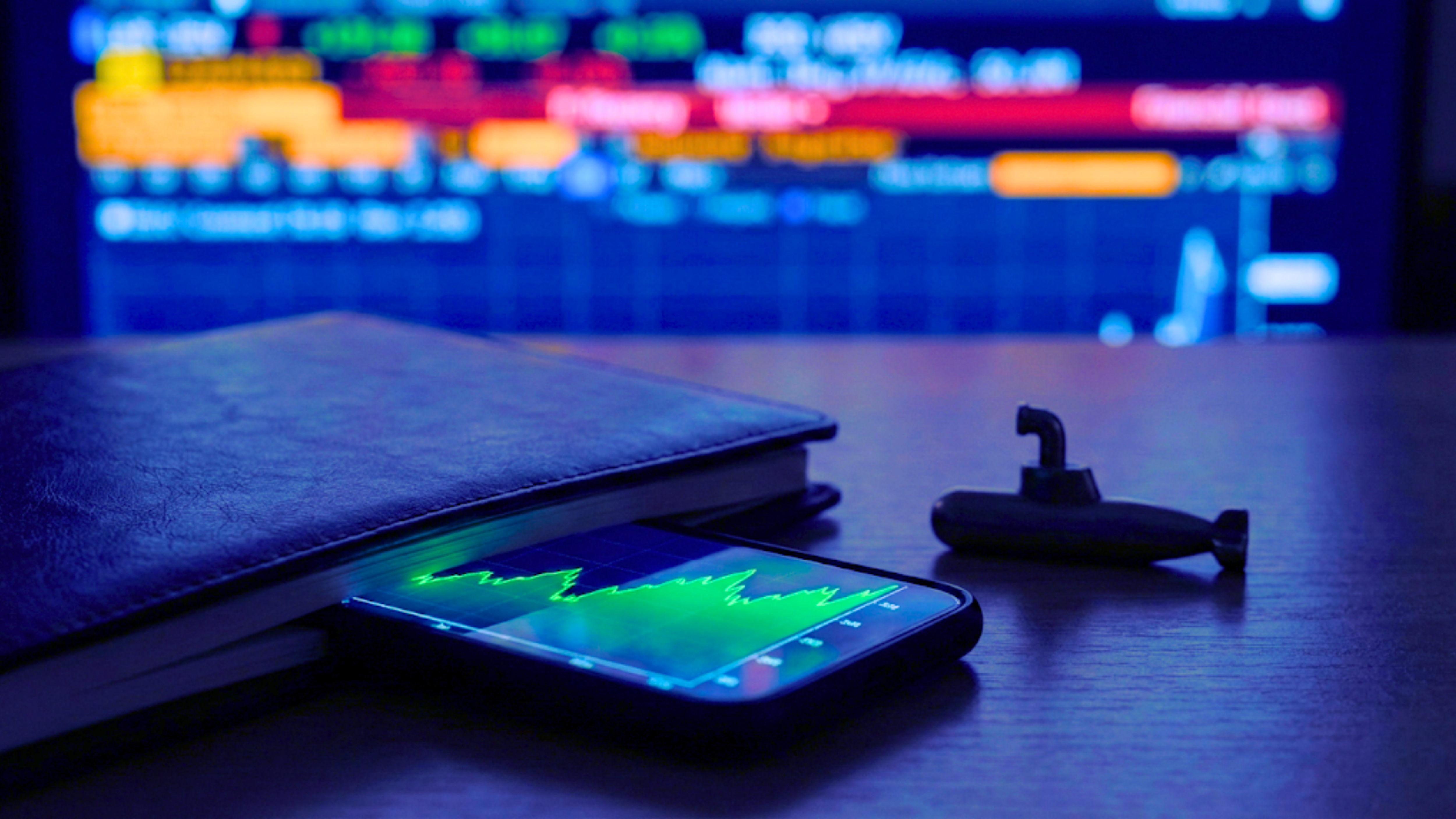 Smartphone displays rising stock chart beside notebook as market screen hints at under-the-radar earnings winners.