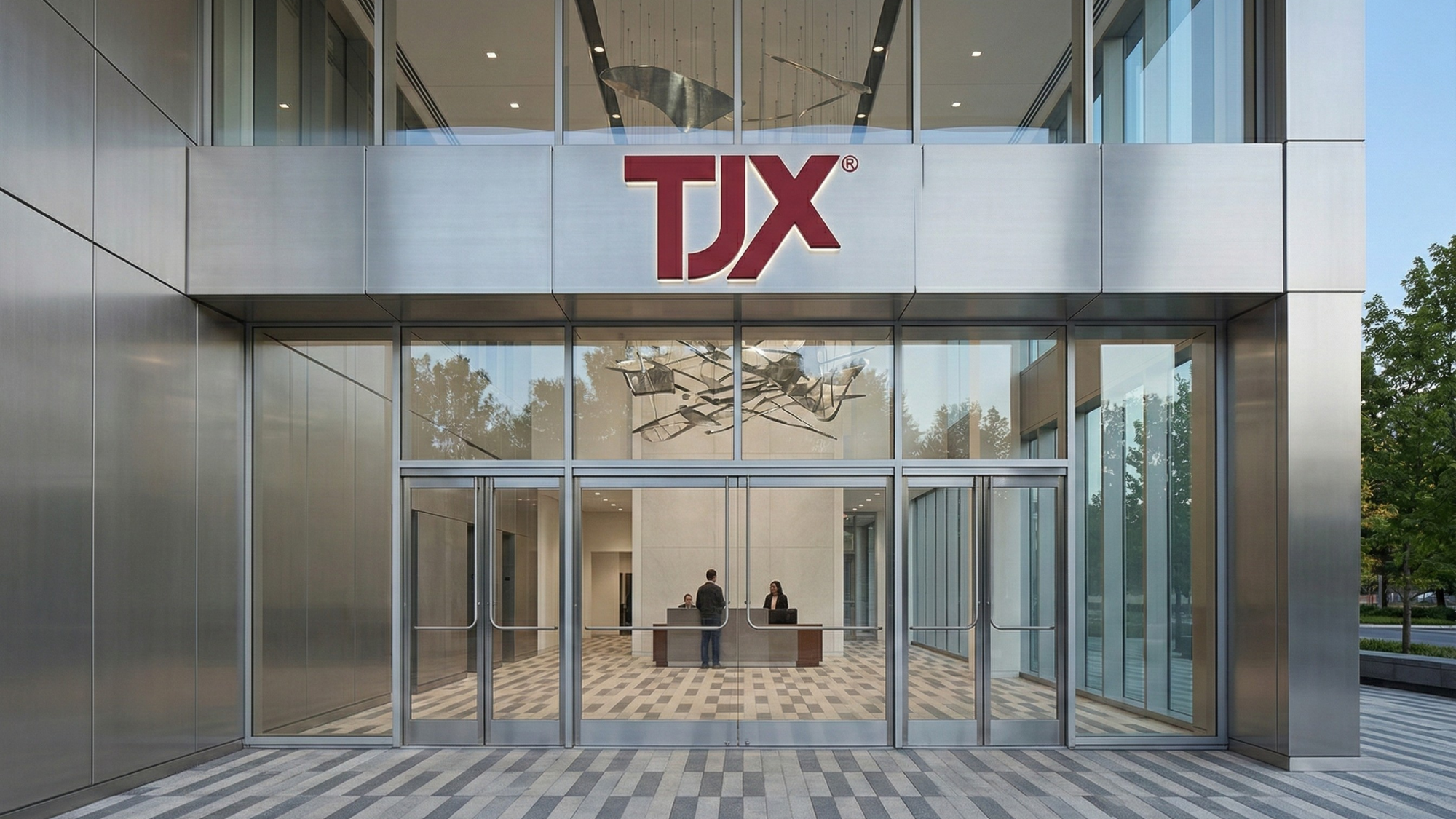 TJX office entrance with red logo above glass doors, corporate headquarters exterior.