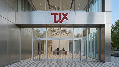 TJX office entrance with red logo above glass doors, corporate headquarters exterior.