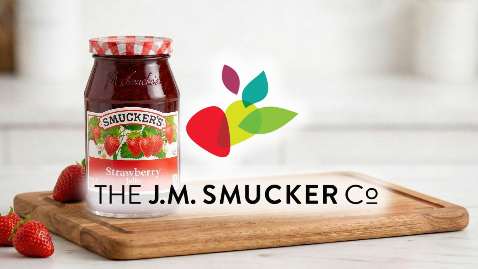 Strawberry Smucker’s jelly jar on wooden board with large J.M. Smucker logo overlay in kitchen setting