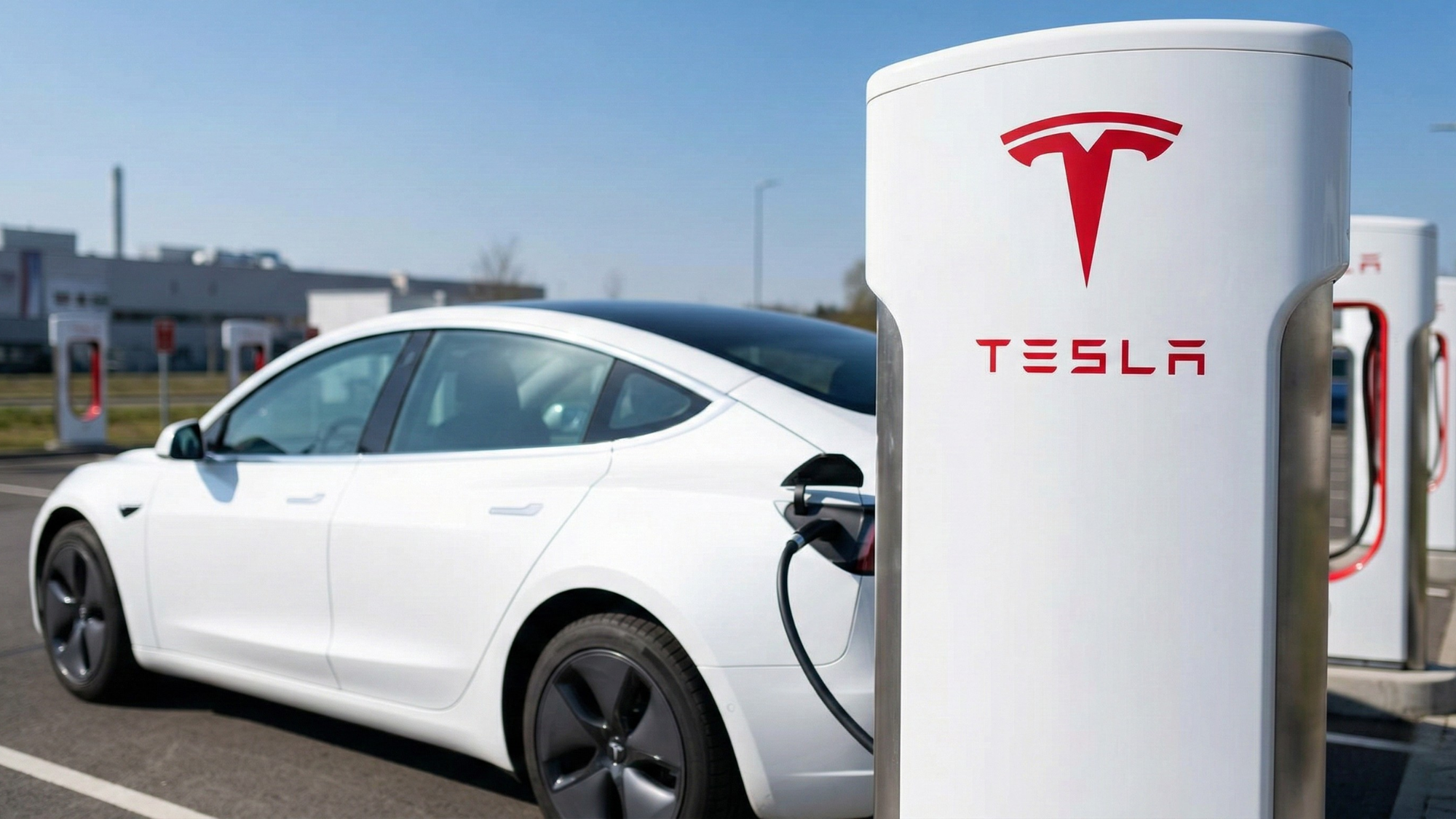 White Tesla Model 3 charging at a Tesla Supercharger station, highlighting the electric vehicle industry and FSD regulatory focus.