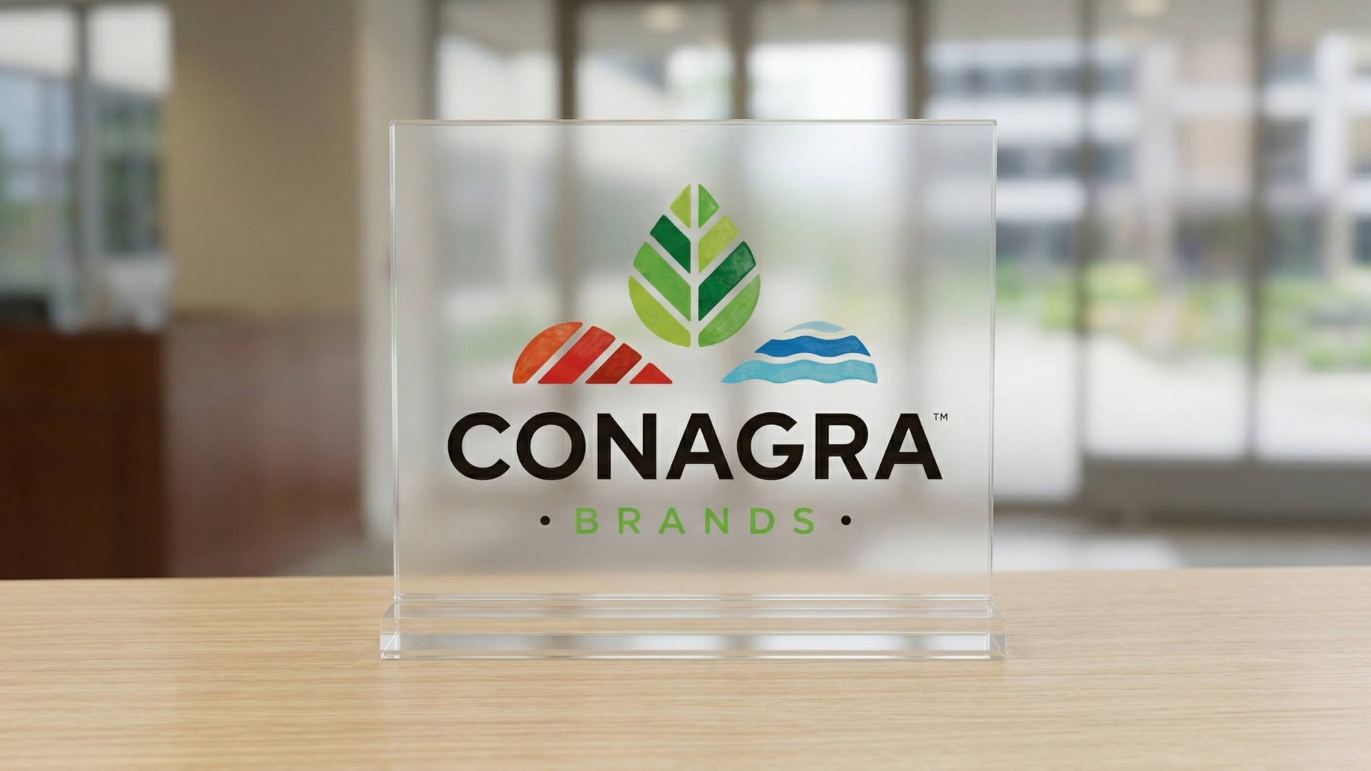Conagra Brands logo displayed on a clear glass plaque, symbolizing packaged food industry and stock rebound potential.