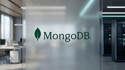 MongoDB logo displayed on a frosted glass wall in a modern office setting with server racks visible.