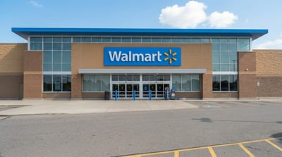 Exterior view of a Walmart store entrance with the company logo and empty parking lot.