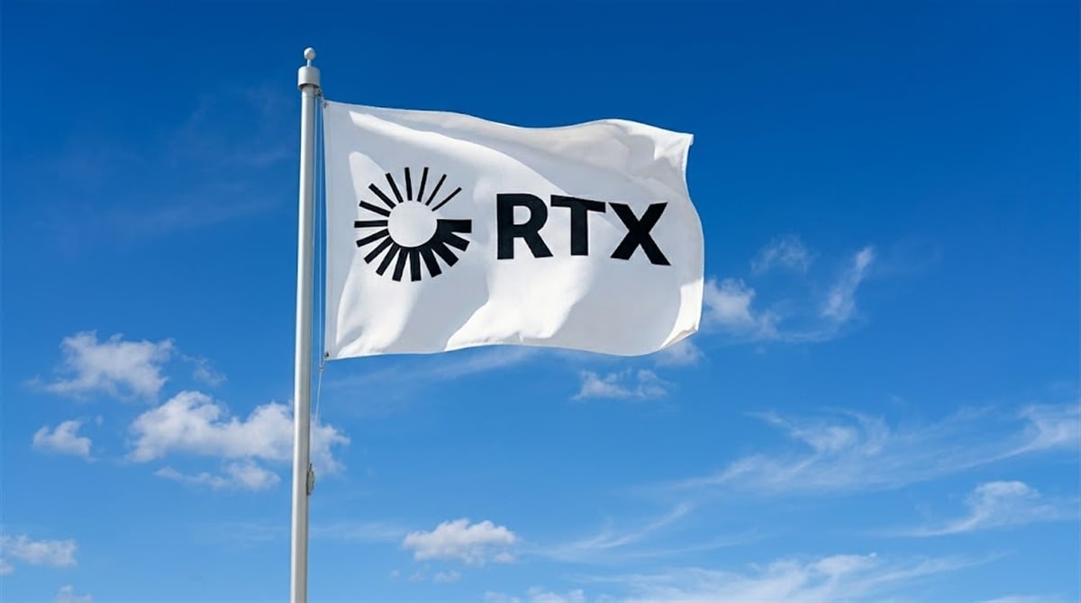 A white flag bearing the RTX Corporation logo flies on a flagpole against a blue sky.
