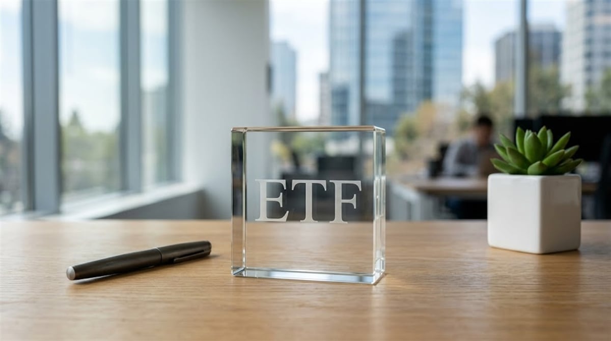 A glass cube engraved with "ETF" sits on a wooden desk in a modern office setting.