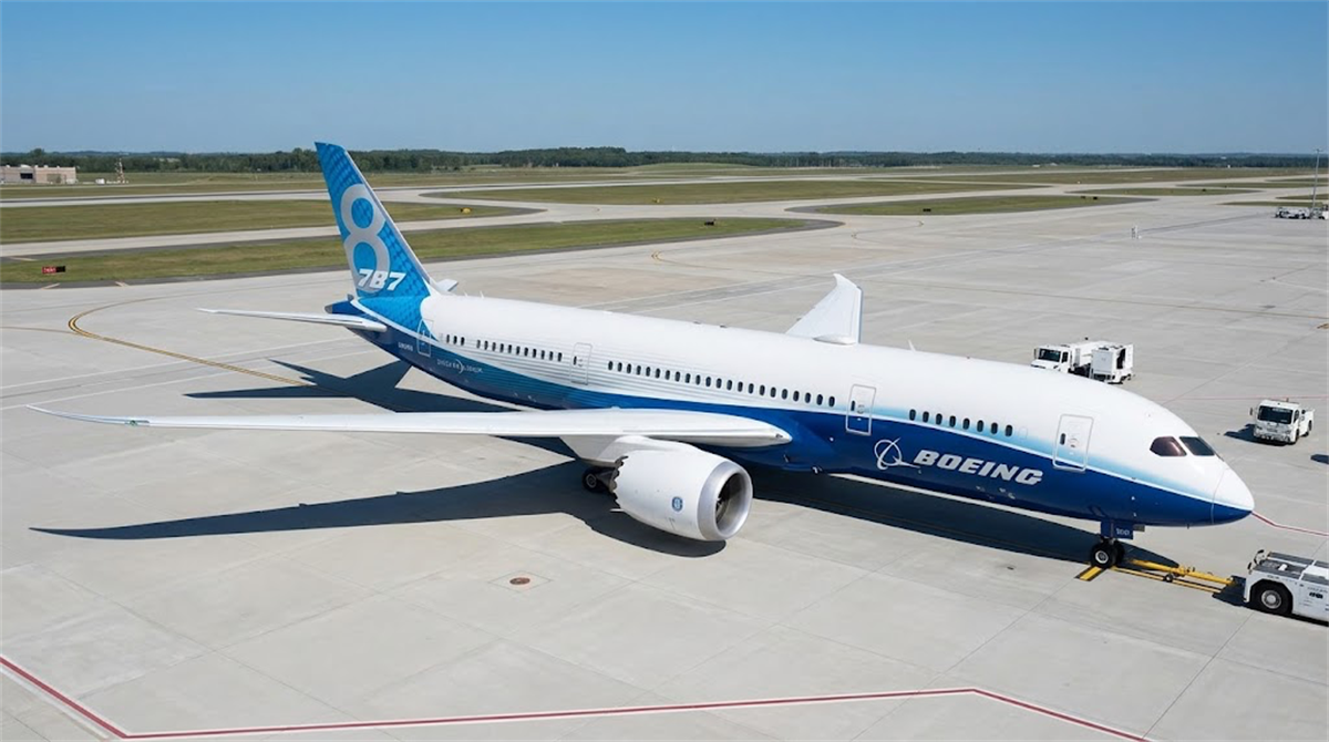 A Boeing 787-8 Dreamliner aircraft in Boeing house livery sits on an airport tarmac.