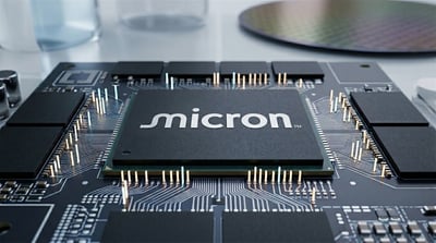 Micron Technology branded semiconductor chip mounted on a circuit board with a silicon wafer in the background.