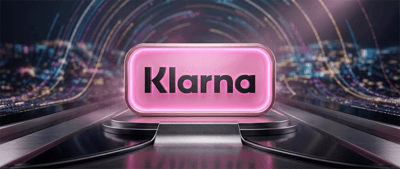 Klarna logo displayed on an illuminated pink sign against a futuristic cityscape backdrop.