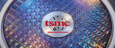 TSMC logo displayed on a silicon wafer against a background of a patterned semiconductor chip surface.