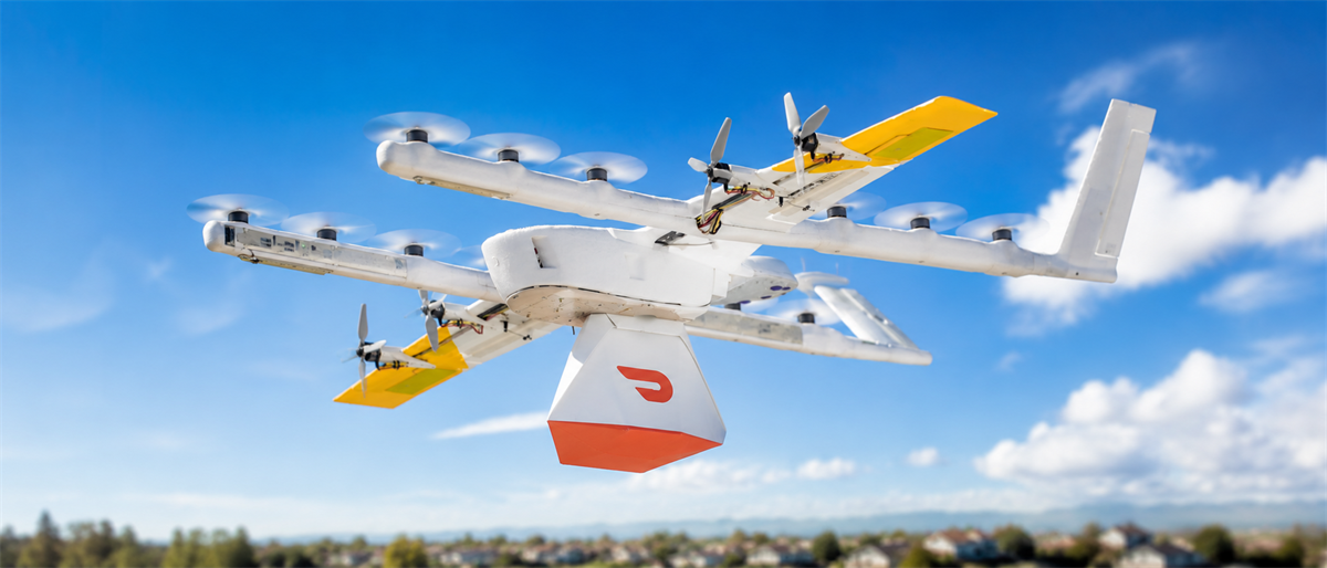 A DoorDash-branded delivery drone with a red and white cargo pod flies against a blue sky.