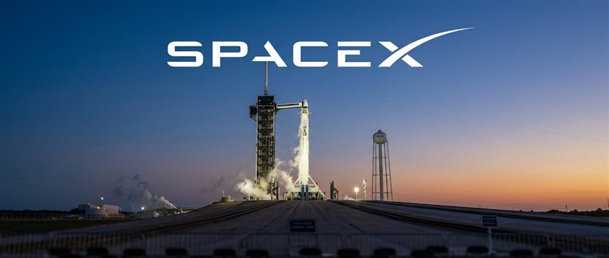 SpaceX logo above a rocket on a launch pad at twilight, with a water tower in the background.
