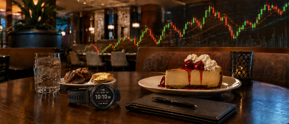 Restaurant table with cheesecake, dessert, water glass, smartwatch, and notebook overlaid with a stock candlestick chart.