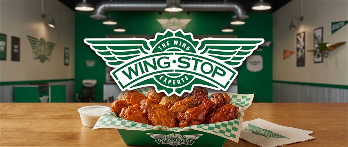 Wingstop logo displayed over a basket of chicken wings inside a restaurant dining area.