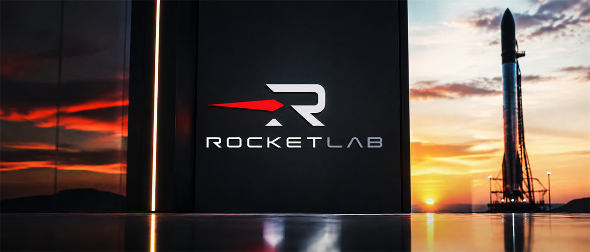 Rocket Lab logo displayed on a sign with a rocket on a launch pad at sunset in the background.