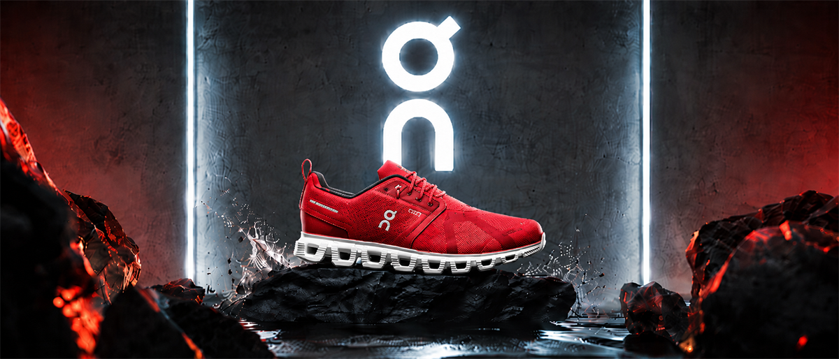 A red On running shoe displayed on dark rocks with the On logo illuminated in the background.