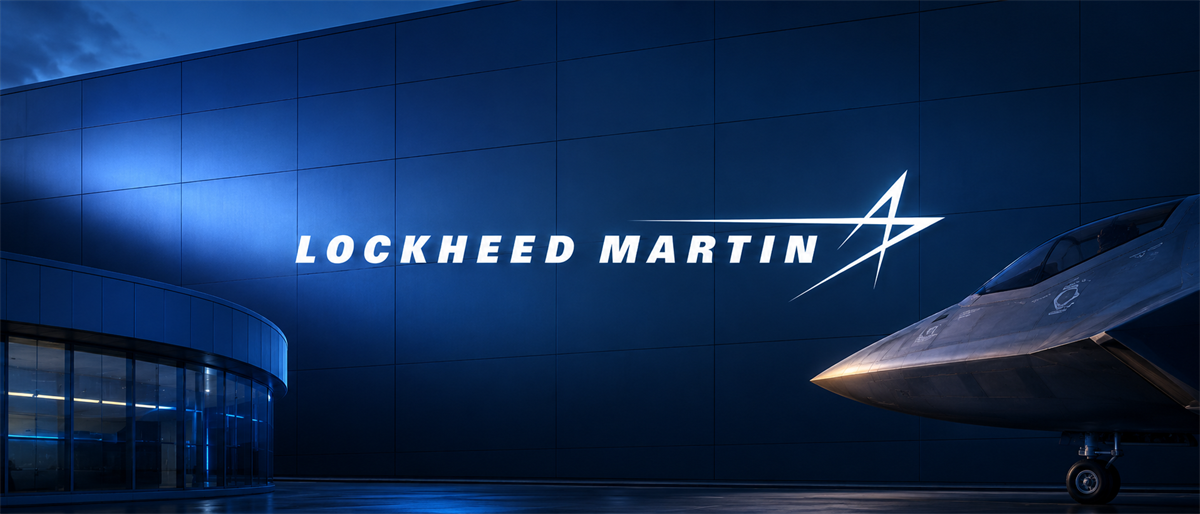 Lockheed Martin logo illuminated on a building exterior at night, with an aircraft nose visible nearby.