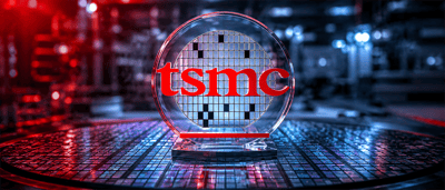 TSMC logo displayed on a glass semiconductor wafer sculpture resting atop a silicon wafer surface.