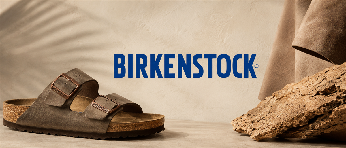 Birkenstock logo displayed beside a two-strap sandal, cork material, and leather, with a neutral tan backdrop.