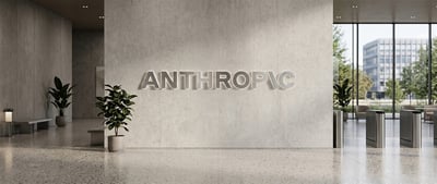 Office lobby with the Anthropic logo mounted on a concrete wall, potted plants, and glass entrance doors.