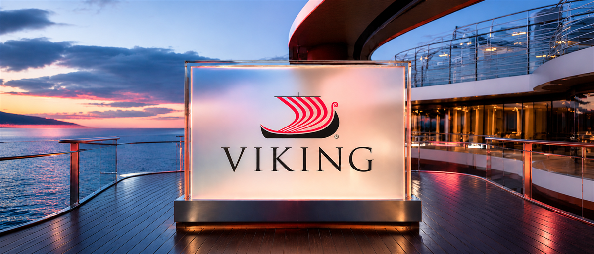 Viking logo displayed on a lit sign on a cruise ship deck at sunset overlooking the ocean.